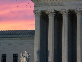 Photograph of the supreme court of the U.S. building, lit ominously from below during sunset.