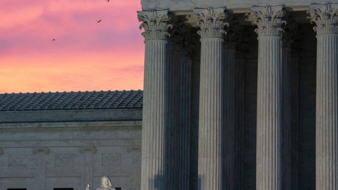 Photograph of the supreme court of the U.S. building, lit ominously from below during sunset.