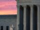 Photograph of the supreme court of the U.S. building, lit ominously from below during sunset.