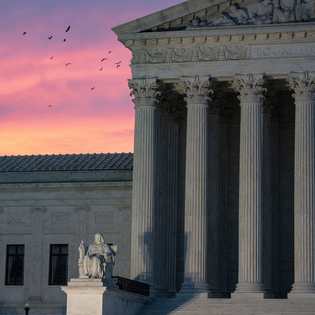 Photograph of the supreme court of the U.S. building, lit ominously from below during sunset.