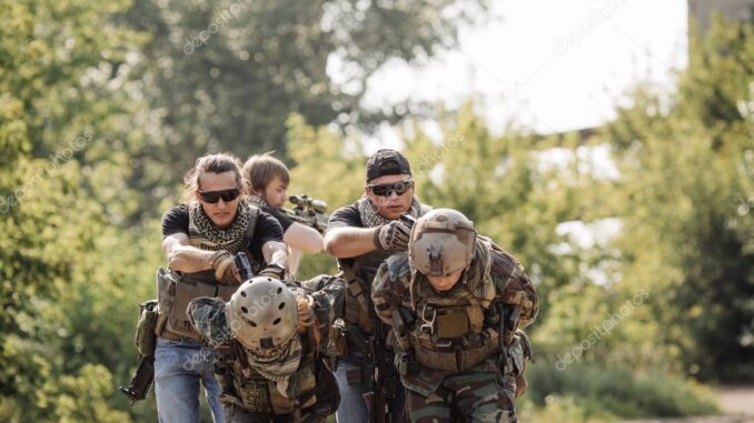 Photograph of men in fatigues and combat helmets being held hostage from behind by men in armored vests and sunglasses pointing pistols at the napes of their necks.