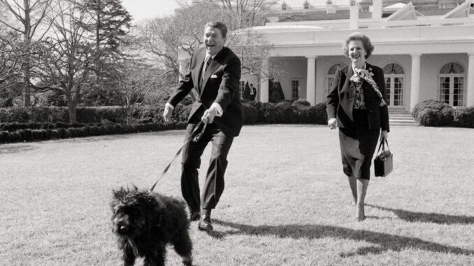 Black and white photo of Ronald Reagan being pulled across the White House lawn by a leashed dog while standing next to Nancy Reagan