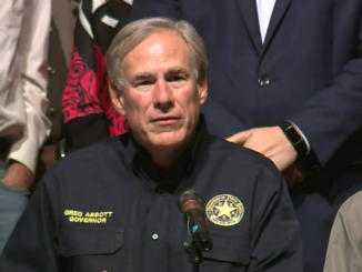 Greg Abbott at a microphone wearing a police-style jacket with a star on the breast