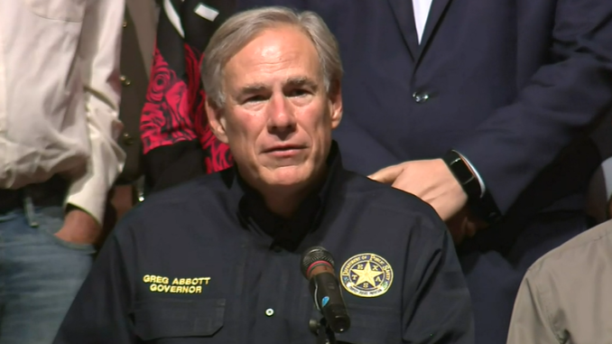 Greg Abbott at a microphone wearing a police-style jacket with a star on the breast