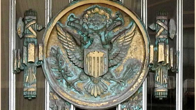 A large wall hanging of the US's official eagle seal surrounded on both sides by Roman fascia, a famous symbol of fascism