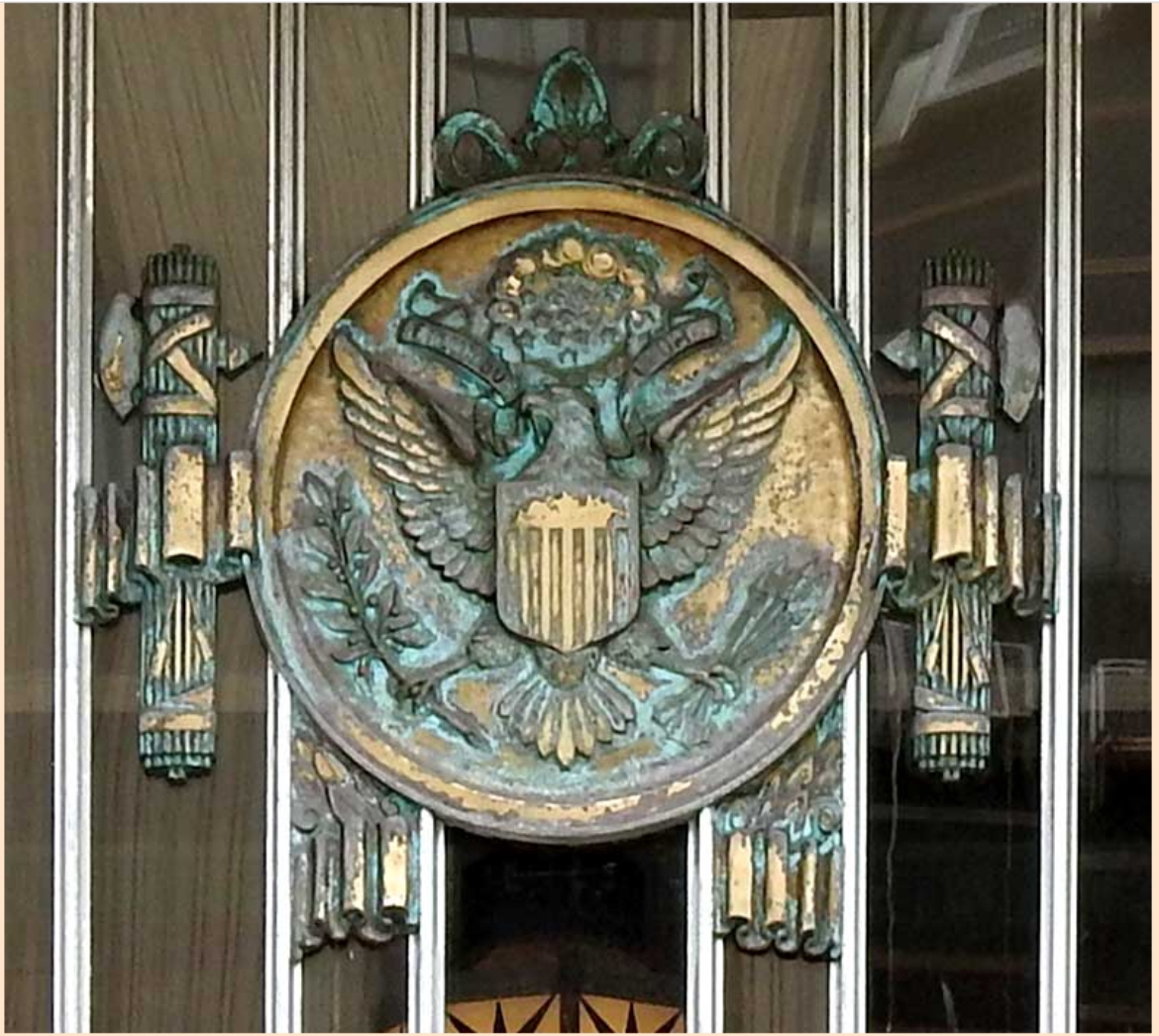 A large wall hanging of the US's official eagle seal surrounded on both sides by Roman fascia, a famous symbol of fascism